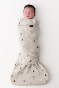 Baby in a Harry Potter patterned cream sleep bag swaddler on a white background