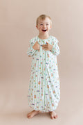 Child wearing a green and white striped sleep bag walker with colorful Harry Potter patterns on a beige background