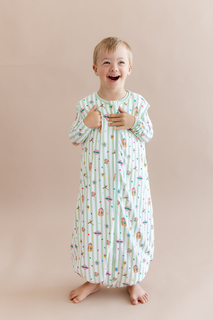 Child wearing a green and white striped sleep bag walker with colorful Harry Potter patterns on a beige background