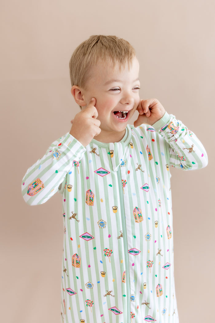 Child wearing a green and white striped sleep bag walker with colorful Harry Potter patterns on a beige background