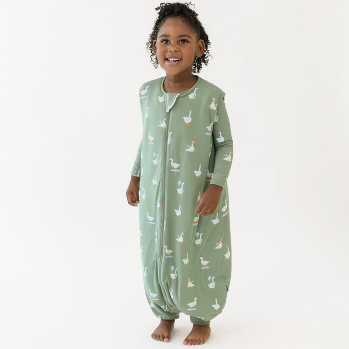 Young girl standing wearing the Sleep Bag Walker in Silly Goose 1.0 with matching long sleeve toddler pajamas on underneath
