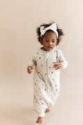 Child wearing a Harry Potter patterned sleep bag walker with white headband on a beige background