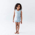 Standing toddler wearing Kyte Baby  Sleeveless Bodysuit in Fog with matching bottoms
