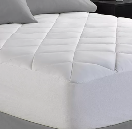 A Spring Air Illuna Plush Comfort mattress pad, neatly arranged on a bed, featuring a quilted design that offers additional cushioning for comfort and improved sleep quality.