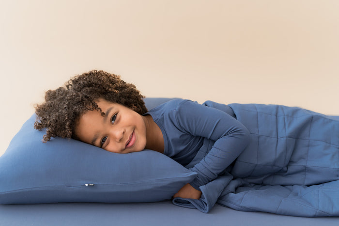 Boy lying on on Standard Pillowcase in Oxford wearing similar color shirt and covered with Oxford blanket