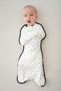 Baby wearing Swaddle bag in Midnight Polka Dot print on a beige background