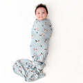 Newborn swaddled in the Swaddle Blanket in Mallard Duck laying on a white surface