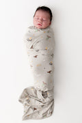 Baby wrapped in a beige swaddle blanket with Harry Potter prints on a white background.