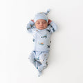 Newborn laying on a white surface wearing the Take Me Home Set with Cap in Take Off