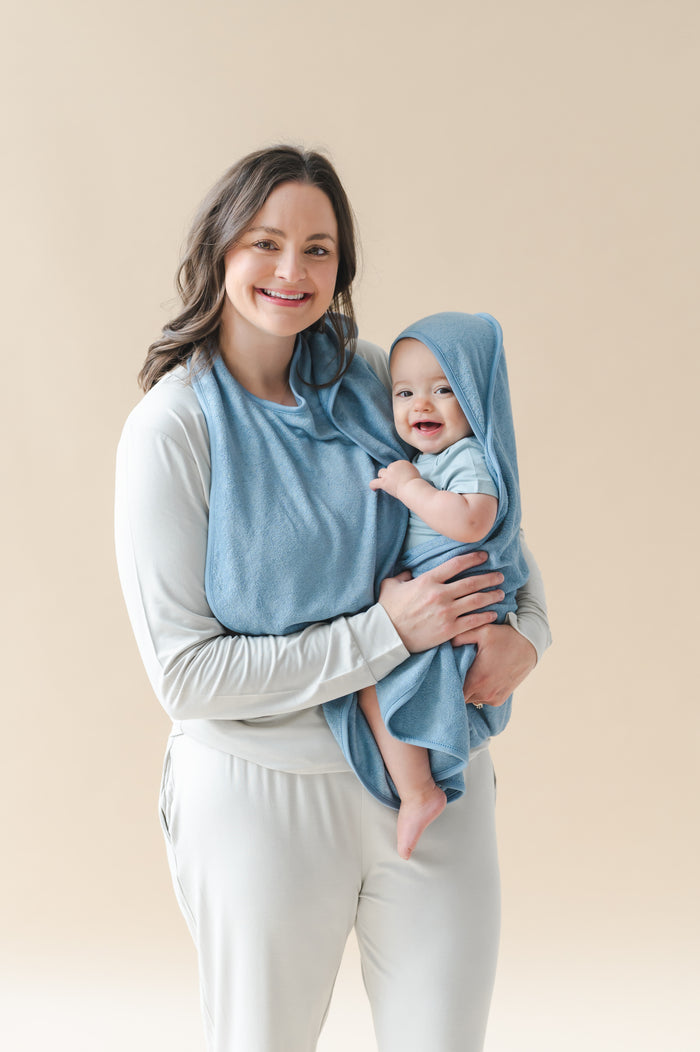 Mother holding infant wearing the Terry Apron Towel in Slate