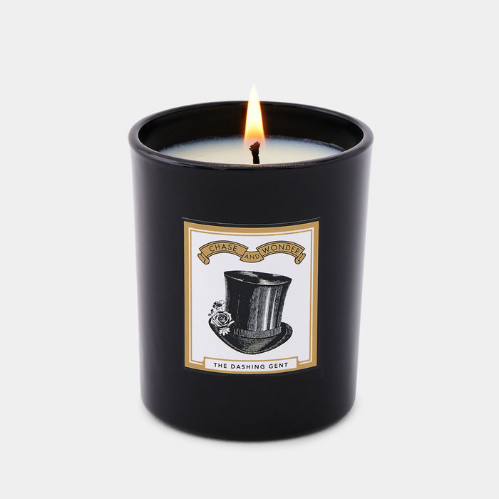 The Dashing Gent scented glass candle lit, warm glow through black glass