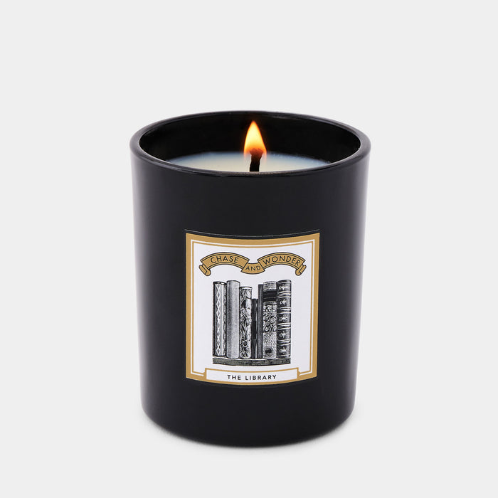 The Library Scented scented glass candle lit, warm glow through black glass