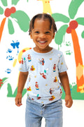 Girl wearing Toddler Basic Tee in Curious George print over a blue jeans smiling in front of a colorful background