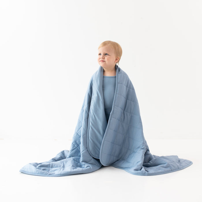 Child wrapped in Kyte Baby TOG 1.0 Toddler Blanket in Slate gray blue