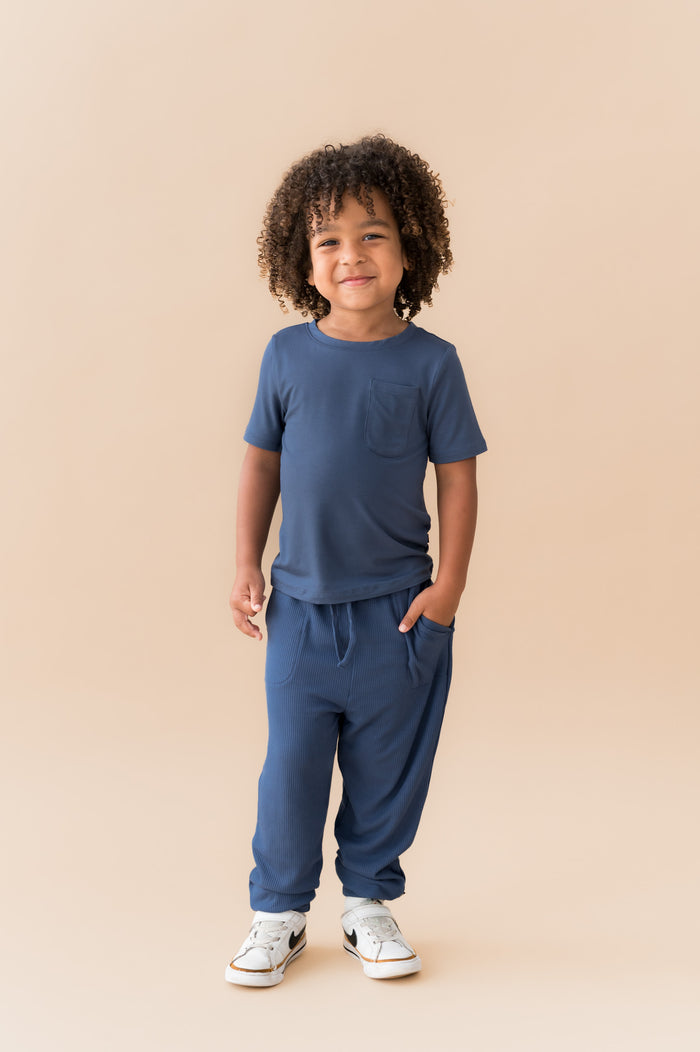 Child posing in Ribbed Jogger Pant in Oxford under Toddler Crew neck tee on a beige background