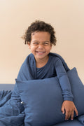 Boy holding Toddler Pillowcase in Oxford sitting with similar color blanket and wearing Oxford shirt