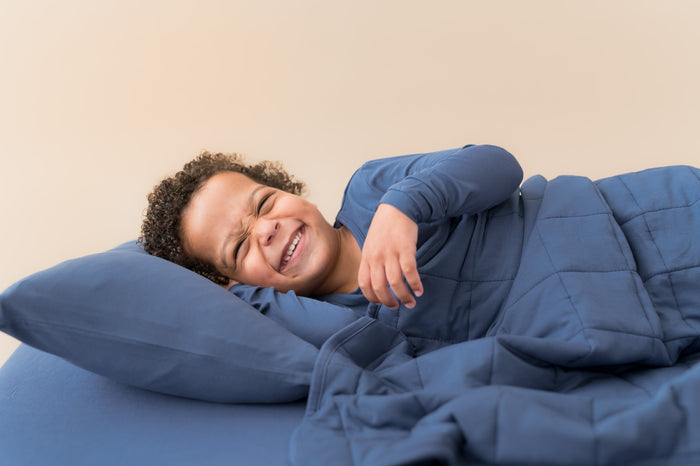Boy lying on bed over Toddler Pillowcase and sheet in Oxford covered with similar color blanket and wearing Oxford shirt