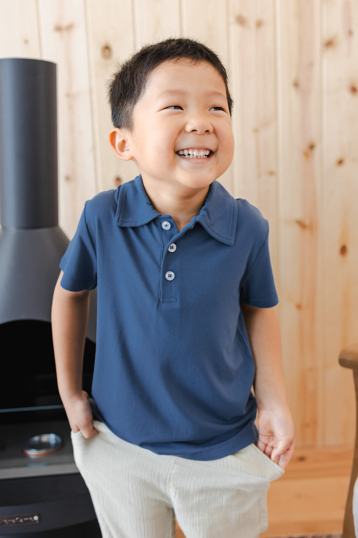 Toddler smiling in Toddler Short Sleeve Polo in Oxford over white pants