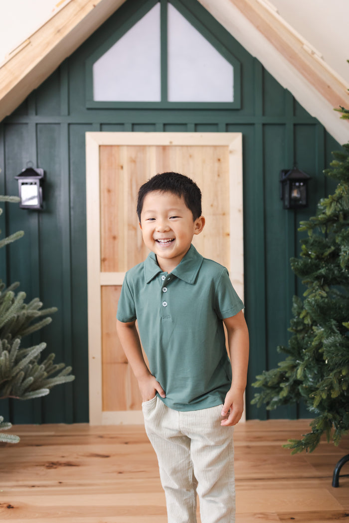Toddler standing in front of door wearing Toddler Short Sleeve Polo in Pine over off white pants