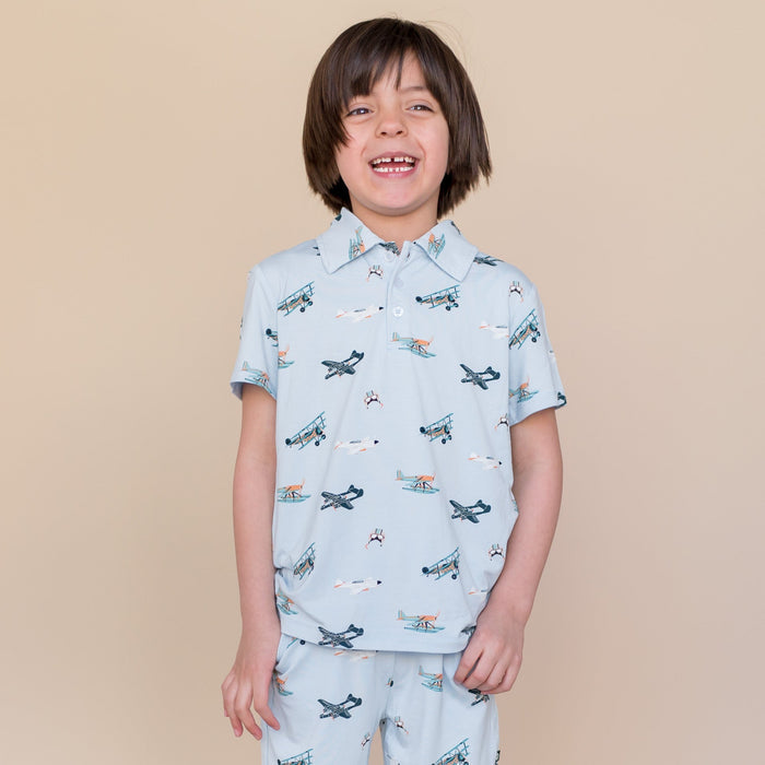 Smiling boy wearing the Toddler Short Sleeve Polo in Take Off with matching shorts