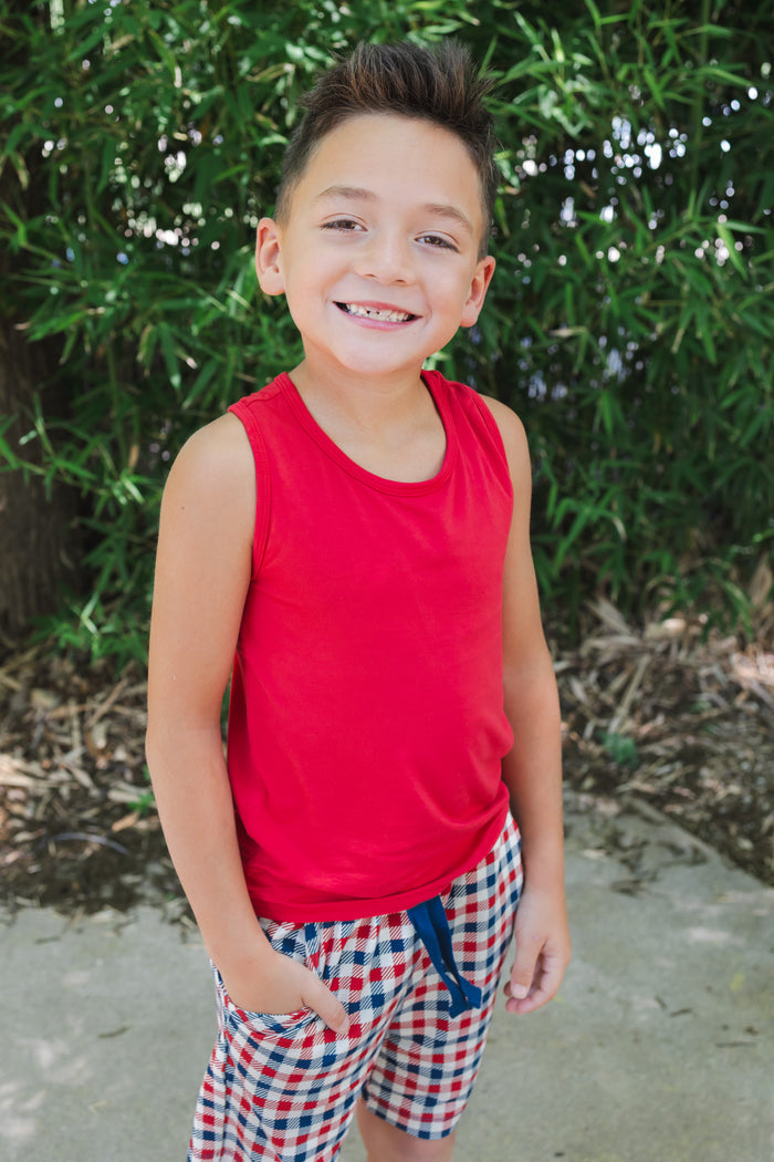 Child smiling wearing a Cardinal tank top over a red blue and white Patriotic Gingham check print drawstring shorts outdoors