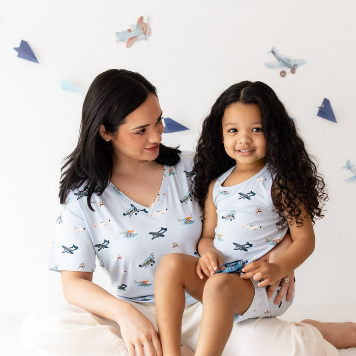Young girl wearing the Toddler Tank Top in Take Off sitting on her mothers lap who is wearing a matching women's v-neck