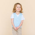 Young model wearing the Tuxedo Vest in Breeze over top of a white vneck paired with khaki pants