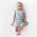 Smiling infant wearing the Twirl Bodysuit Dress in Mallard Duck