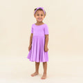 toddler wearing in kyte baby twirl dress in poi with matching bow