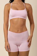 Person wearing a pink scoop bra and shorts set on a beige background