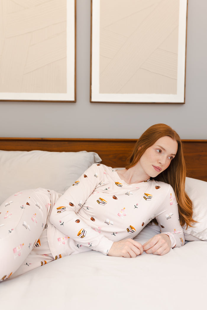 Modal wearing Women's Jogger Pajama Set in Book Club print lying on a bed