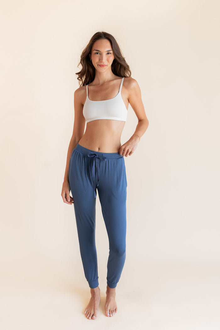 Model wearing Women's Jogger Pants in Oxford under a white bralette top on a beige background