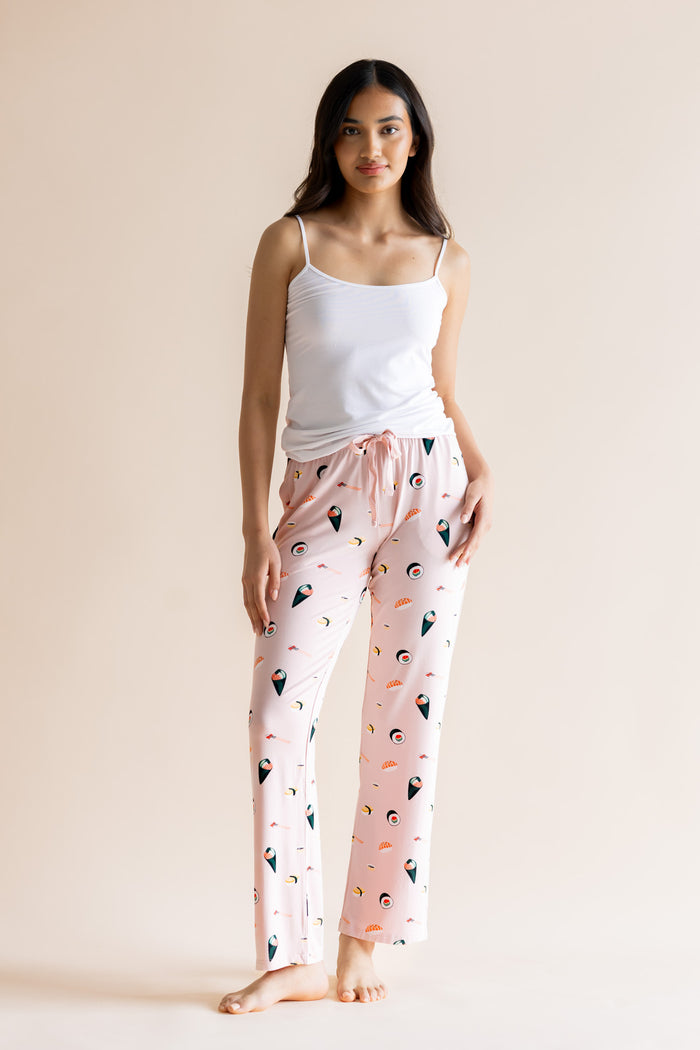 Model posing in pink Women's Lounge Pants in Sushi print under white camisole on a beige background