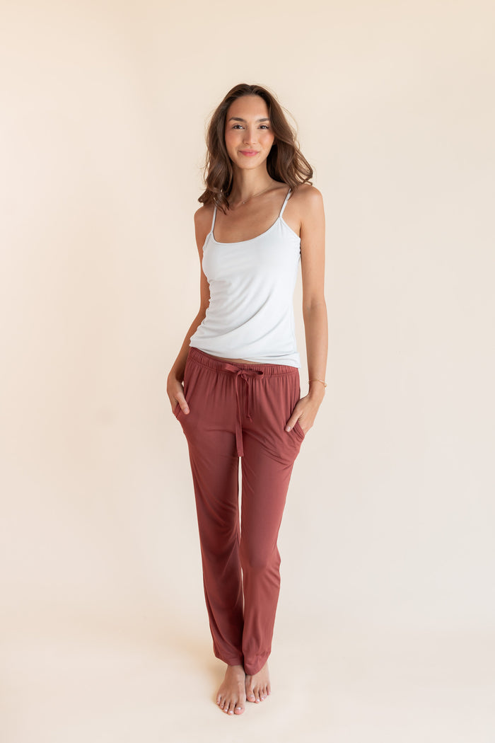 Model wearing Women's Lounge Pants in Ember under white camisole on a beige background