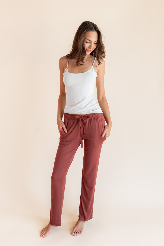 Model posing in Women's Lounge Pants in Ember under white camisole on a beige background