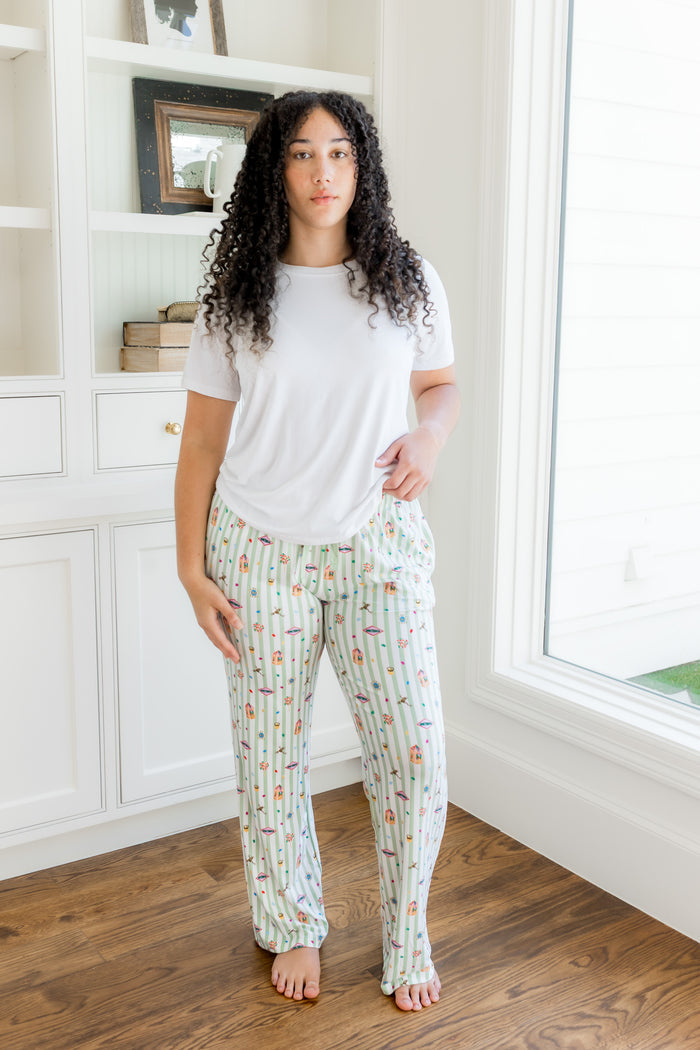 Model standing in a room wearing a green and white striped Women's lounge pants with colorful Harry Potter patterns with a white tee shirt.