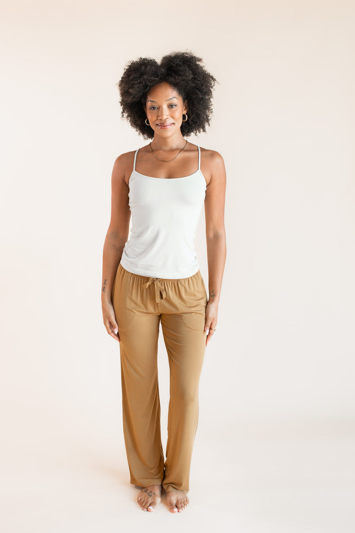 Model posing in Women's Lounge Pants in Ochre under white camisole on a beige background