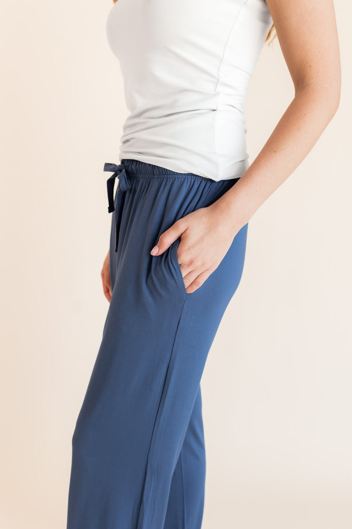Model showcasing pockets on Women's Lounge Pants in Oxford under a white camisole on a beige background