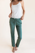 Model wearing Women's Lounge Pants in Pine under white camisole on a beige background