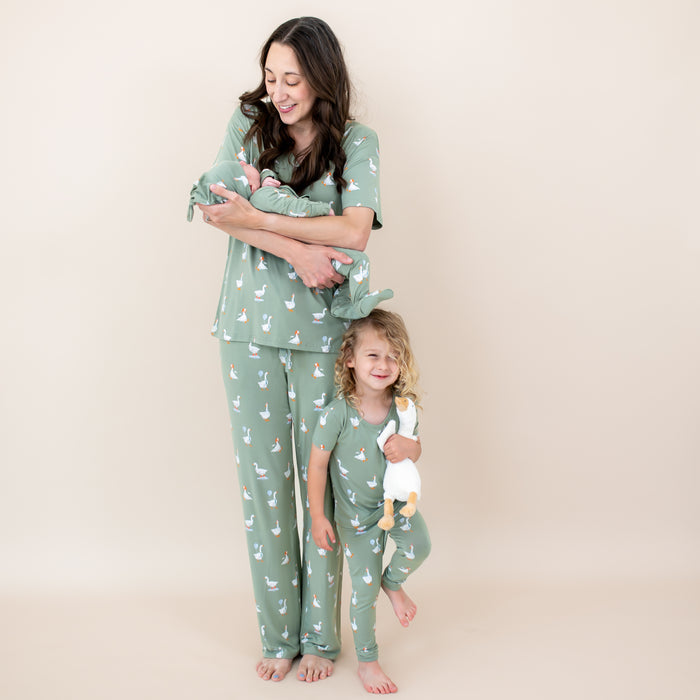 Family matching in Silly Goose. Mother wearing the Women's Lounge Pants in Silly Goose and women's v-neck holding her newborn baby wearing the take me home set and standing beside her oldest child who is in the short sleeve with pants pajama set holding a stuffed toy goose