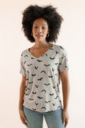 Modal wearing Women's Oversized V-Neck Tee in Bats print over light blue jeans on a beige background