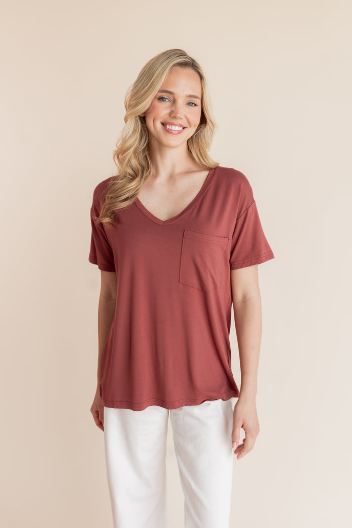 Model wearing Women's Oversized V-Neck Tee in Ember over white pants on a beige background