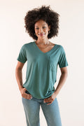 Model wearing Women's Oversized V-Neck Tee in Pine over blue jeans on a beige background