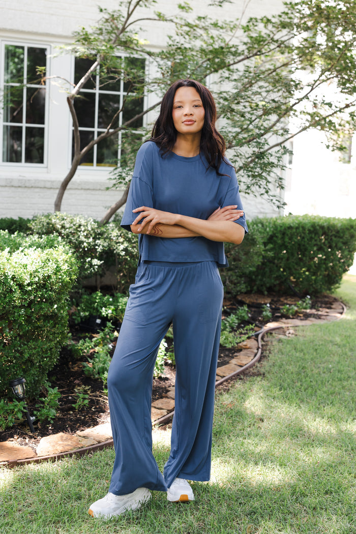 Modal wearing Women's Wide Leg Pant in Oxford standing outdoors in a garden with hands folded