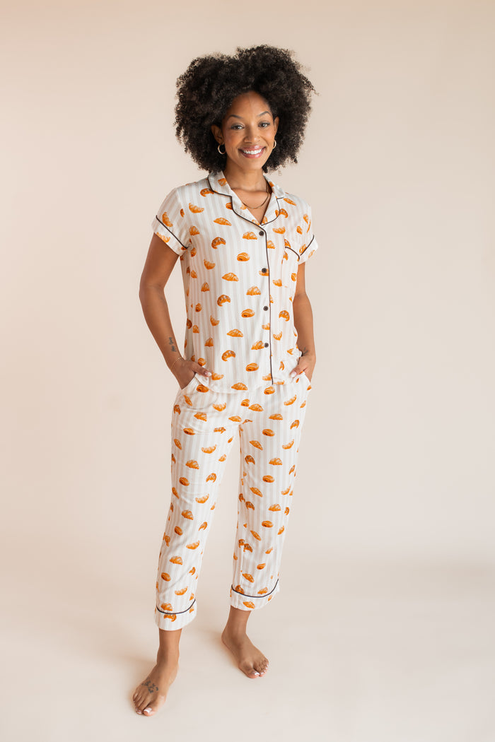 Model posing in Women's Short Sleeve Cropped Pajama Set with Croissant print on a beige background