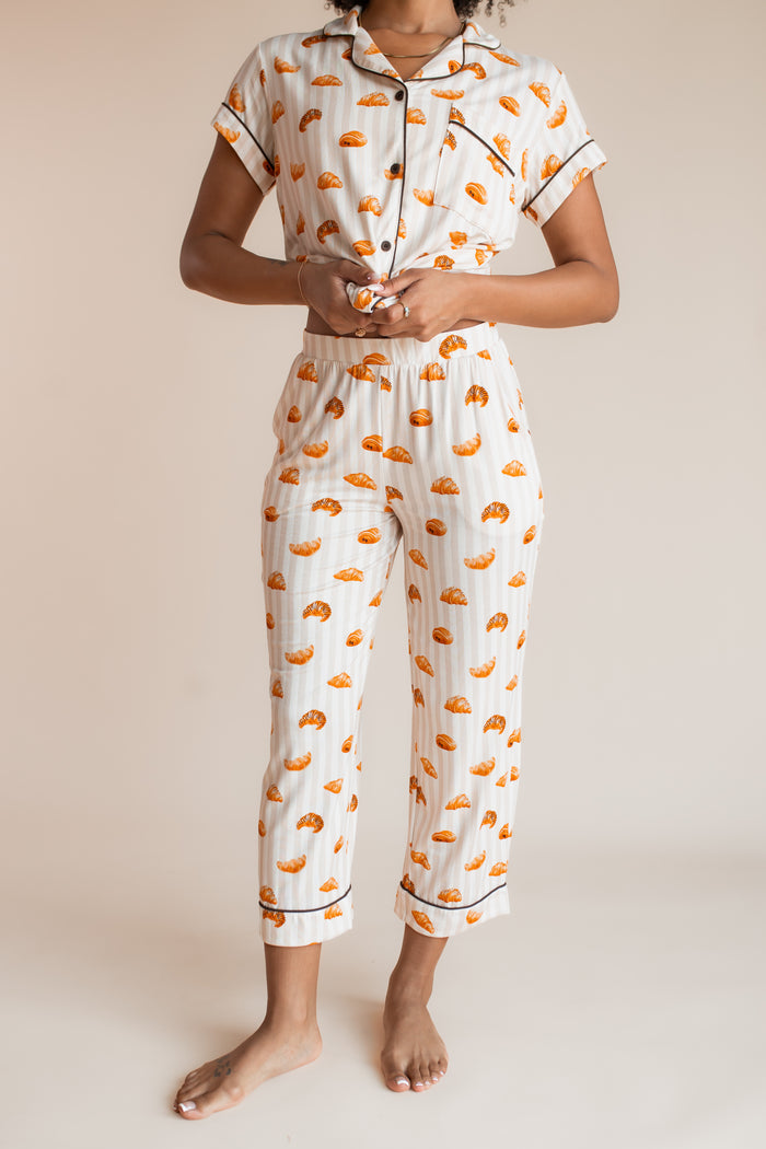 Model showcasing the top part of pajamas of Women's Short Sleeve Cropped Pajama Set with Croissant print on a beige background