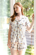 Model posing Women's Short Sleeve Pajama Set in Mickey Mouse & Friends print standing in front of glass door