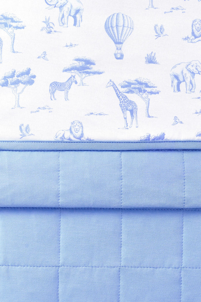 Close up of the Youth Blanket in Toile Safari 1.0 showing the quilted blue backing and smooth printed top layer
