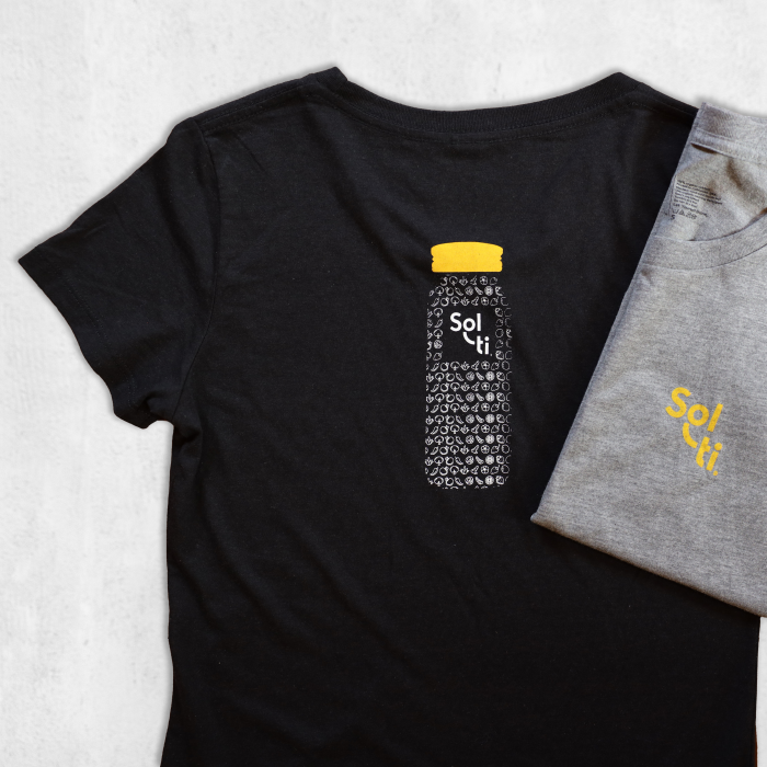 Two Youth Organic Cotton Tees, one in black and one in gray, each featuring the Sol-ti logo with orange text; the black tee also has a design of a bottle filled with SuperFoods and a orange cap on the back shown against a light background