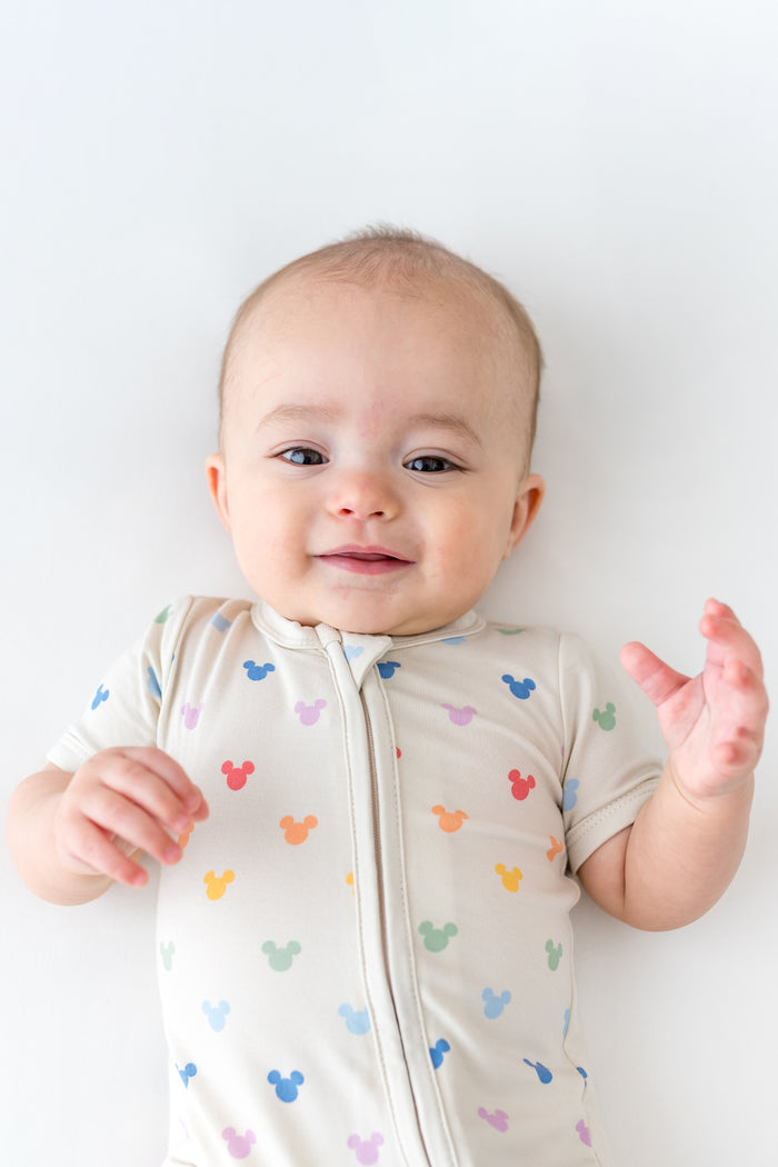 baby in a short sleeve style romper with a zipper in a mickey head pattern